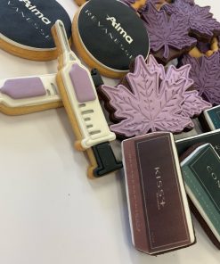 Alma Lasers event fondant decorated cookies. Collection includes Alma Logo on round cookie, product shaped cookie with pack image, syringe shaped cookie with brand colour highlights and a mauve maple leaf shaped cookie